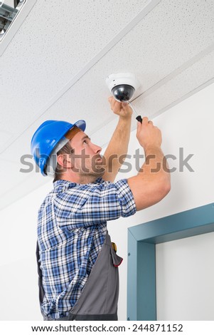 Close-up Of A Technician Adjusting Cctv Camera On Ceiling