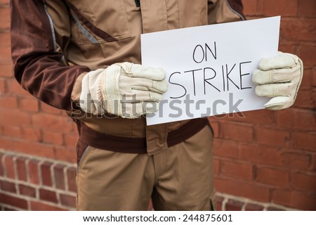 Close-up Of Worker Holding Placard With The Text On Strike Written On It