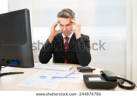 Worried Mid Age Businessman Sitting At Workplace