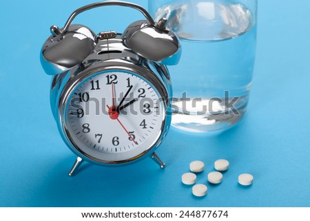 Close-up Of Alarm Clock With Tablets And Glass Of Water