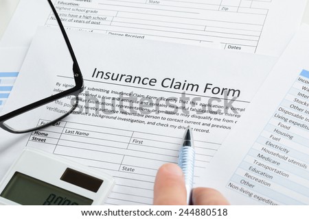 Close-up Of Hand With Pen And Calculator On Insurance Claim Application Form