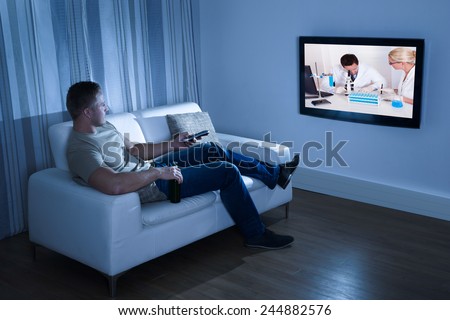 Portrait Of A Man Watching Television Sitting On Couch