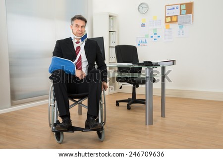 Portrait Of Handicapped Businessman Sitting On Wheelchair In Office
