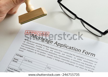 Close-up Of Person Hand With Rubber Stamp And Red Approved Mark On Mortgage Application