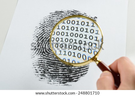 Person Hand With Magnifying Glass Over A Finger Print Revealing Binary Code Within The Print