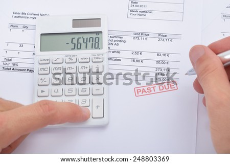 Close-up Of Man Analyzing Past Due Statement Using Calculator