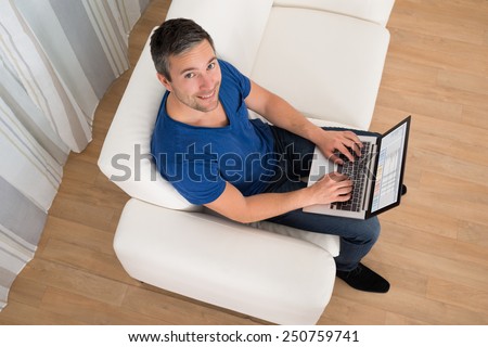 High Angle View Of Man Sitting On Couch Analyzing Graph At Home