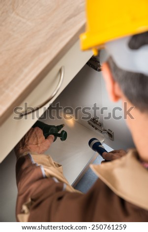 Close-up Of Pest Control Worker Spraying Chemicals With Sprayer In Cabinet