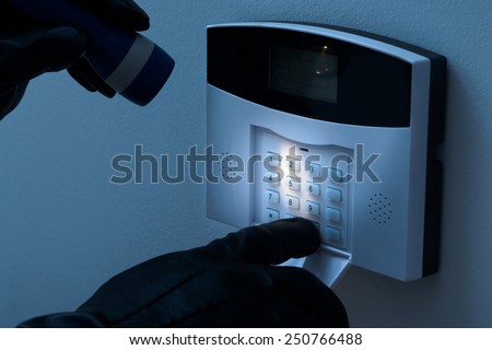 Burglar With Flashlight Trying To Disarm The Security Alarm System