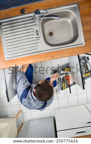 High Angle View Of A Male Plumber Repairing Sink In Kitchen
