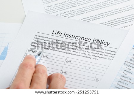 Close-up Of Person Hand Filling Life Insurance Policy Application Form
