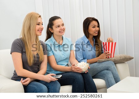 Portrait Of Happy Multiethnic Young Women Sitting On Couch Watching Television