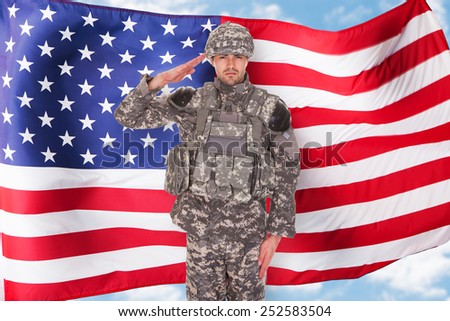 Portrait Of American Soldier Saluting In Front Of Flag