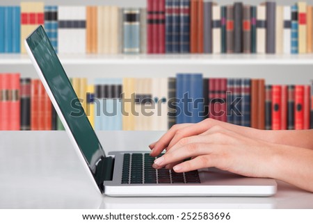 Close-up Of A Person Hands Typing On Notebook In Library