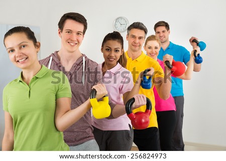 Multiethnic Group Of People Standing In Row Holding Kettle Bell Over White Background