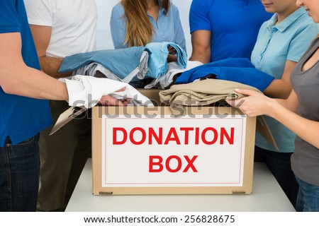 Close-up Of People Putting Clothes Inside Donation Box