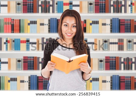 Portrait Of Female Student In Library Reading Book