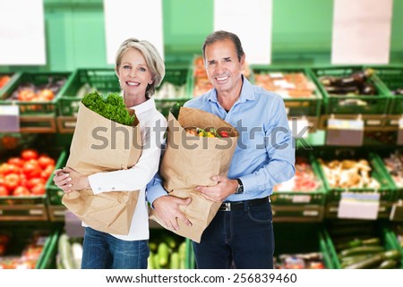 Happy Mature Couple Holding A Grocery Bag Full Of Vegetables