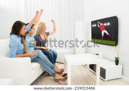 Multiethnic Women Sitting On Couch Cheering Watching Rugby Match