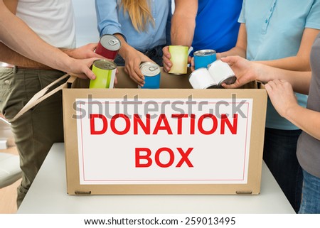Group Of People Putting Cans In Donation Box
