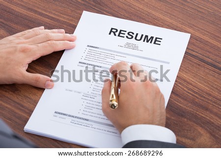 Cropped image of mid adult businessman analyzing resume at desk