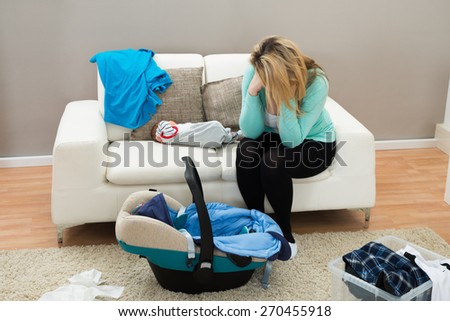 Stressed Mother With The Baby Sitting On Sofa