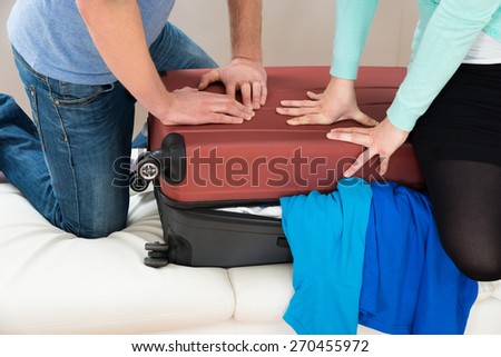 Close-up Of Couple Together Packing Luggage For Vacation