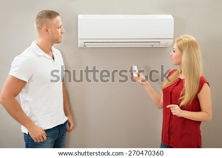 Couple Operating Remote Control Of An Air Conditioner