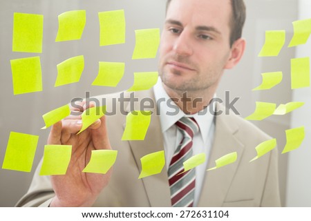 Businessman Looking At Adhesive Notes On Glass Wall