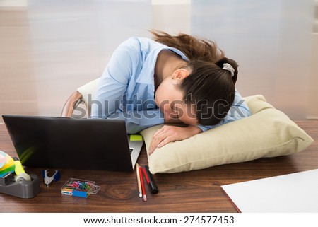 Young Businesswoman Sleeping At Desk In Office