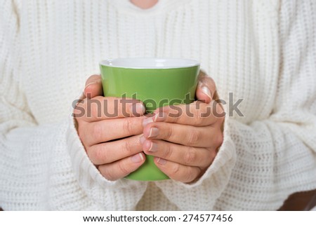Close-up Of Person Hand Holding Green Mug Of Hot Drink