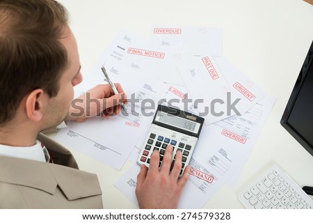 Close-up Of Businessman Calculating Financial Bills With Calculator