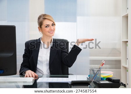 Young Happy Businesswoman In Office Displaying Invisible Product