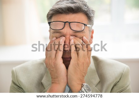 Close-up Of Bored Businessman Rubbing His Eyes