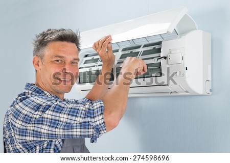 Portrait Of A Happy Male Technician Repairing Air Conditioner