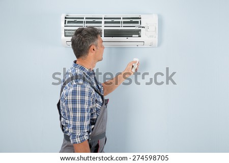Close-up Of A Technician Operating Air Conditioner With Remote Controller