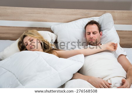 Couple Sleeping With White Duvet In Bed At Home