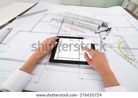 Close-up Of Architect Hands Using Digital Tablet Over Blueprint. Blueprints were created by photographer