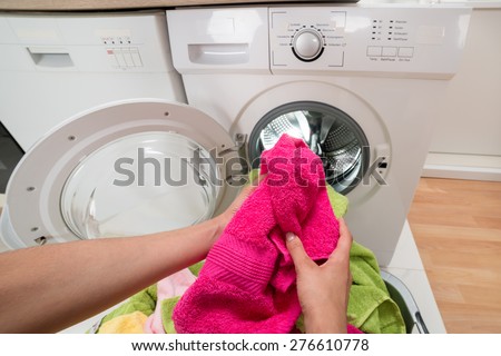High Angle View Of Person Hands Putting Colorful Towels Into The Washing Machine