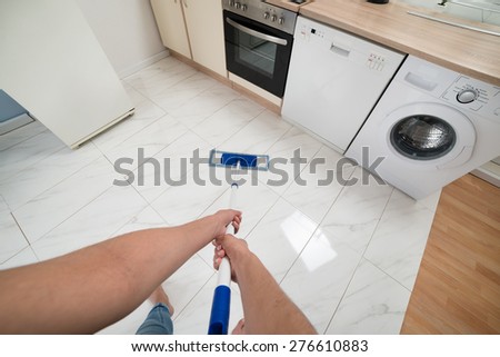 Close-up Of Woman Cleaning Kitchen Floor With Mop