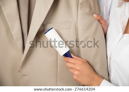 Close-up Of Woman Cleaning Coat With Adhesive Roller