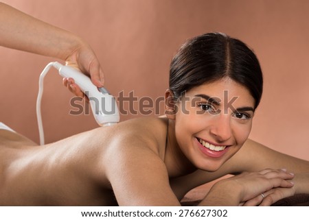 Close-up Of Smiling Young Woman Lying On Front Receiving Epilation Laser Treatment