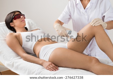 Beautician Giving Epilation Laser Treatment To Woman On Thigh