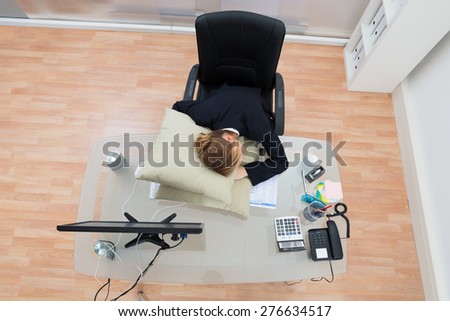 High Angle View Of Businesswoman Sleeping On Pillow At Desk