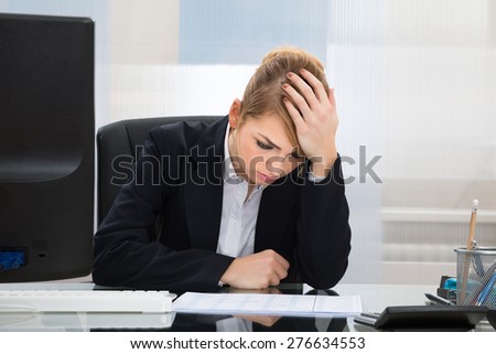 Portrait Of Upset Young Businesswoman Sitting At Desk In Office