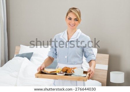 Happy Maid Carrying Breakfast Tray In Hotel Room