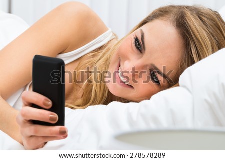 Close-up Of Beautiful Young Woman On Bed Using Cellphone