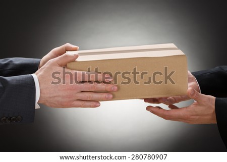 Close-up Of A Businessman Giving Box To His Colleague