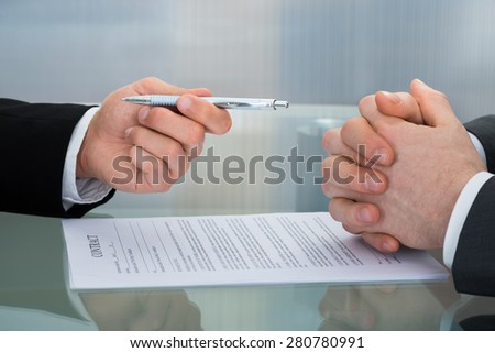 Close-up Of Businessman Giving The Pen To Sign A Contract