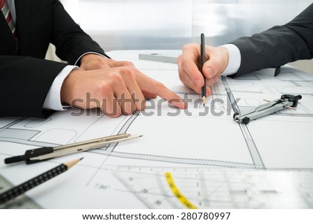 Close-up Of Two Architects Planning Project On Blueprint